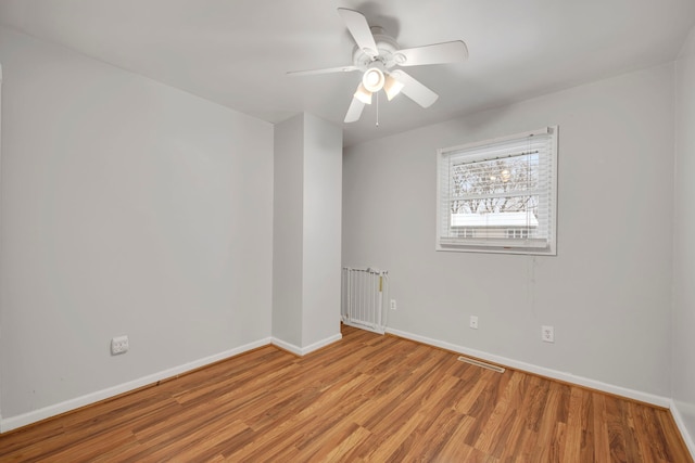spare room featuring visible vents, a ceiling fan, light wood-style flooring, and baseboards