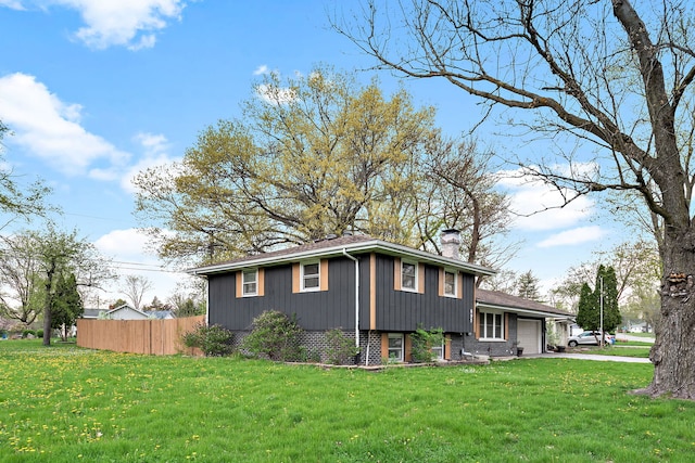 view of side of property with a chimney, a yard, fence, aphalt driveway, and an attached garage