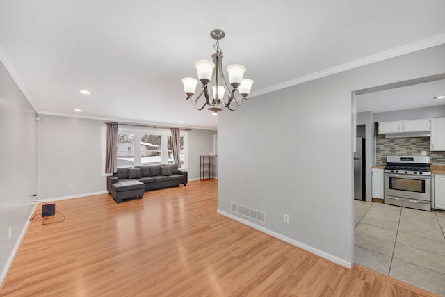 interior space with a chandelier, light wood-style floors, crown molding, visible vents, and baseboards