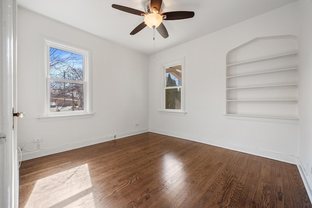 spare room featuring plenty of natural light, wood finished floors, ceiling fan, and baseboards