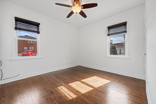 unfurnished room featuring dark wood-style floors, plenty of natural light, and baseboards