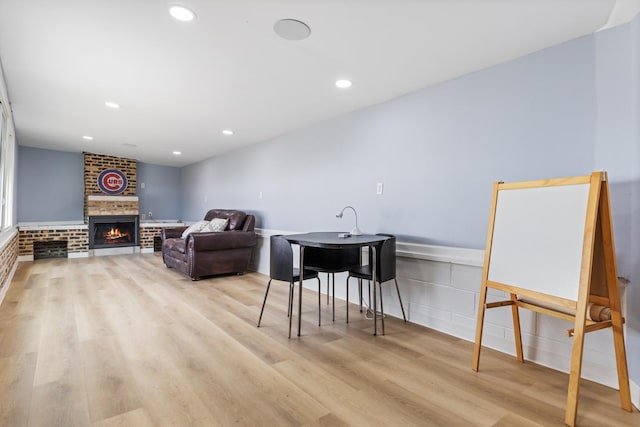 living area with light wood-style flooring, a brick fireplace, and recessed lighting