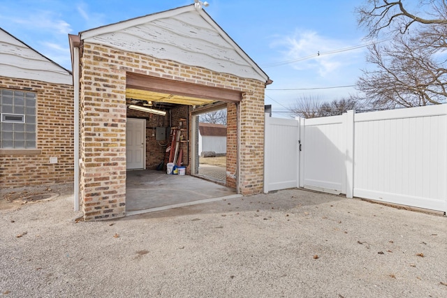 garage featuring fence, a gate, and electric panel