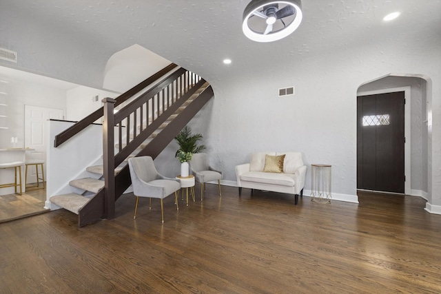staircase featuring arched walkways, wood finished floors, and baseboards