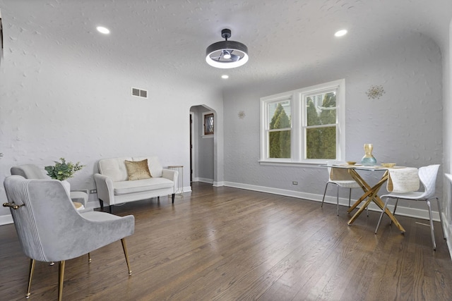sitting room featuring arched walkways, wood-type flooring, baseboards, a textured wall, and recessed lighting
