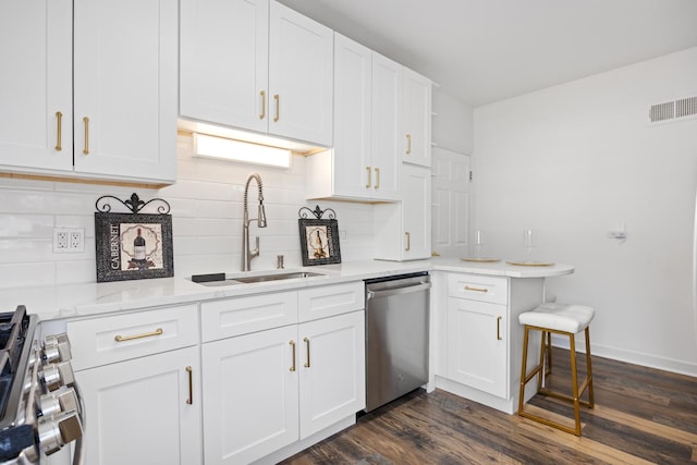 kitchen featuring appliances with stainless steel finishes, a sink, tasteful backsplash, white cabinetry, and dark wood finished floors