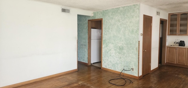 interior space with a textured ceiling, visible vents, baseboards, dark wood-style floors, and ornamental molding
