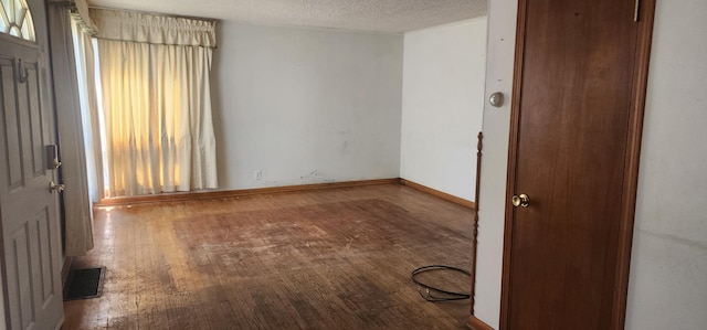 interior space featuring visible vents, baseboards, a textured ceiling, and wood finished floors