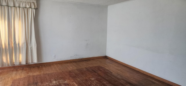 empty room featuring baseboards, a textured ceiling, and wood finished floors
