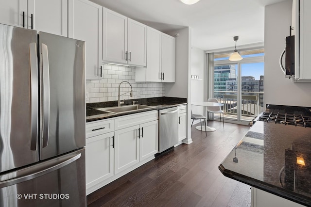 kitchen featuring appliances with stainless steel finishes, a sink, dark wood finished floors, backsplash, and white cabinets