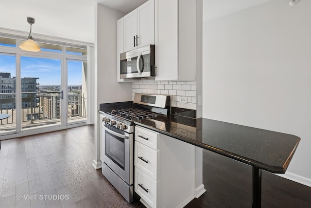 kitchen with appliances with stainless steel finishes, dark wood-type flooring, decorative backsplash, white cabinets, and decorative light fixtures