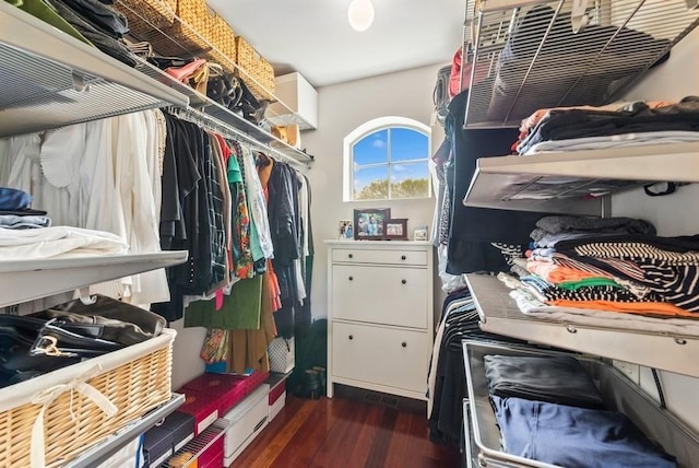 walk in closet with dark wood-style floors