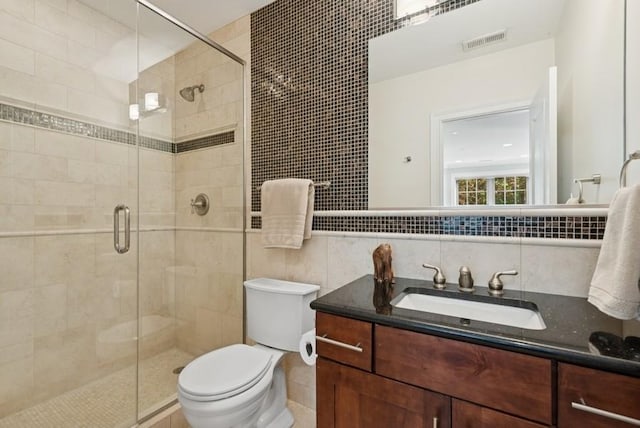 bathroom featuring visible vents, vanity, toilet, tile walls, and a stall shower