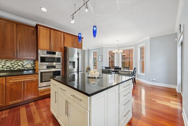 kitchen featuring crown molding, dark wood finished floors, an inviting chandelier, and stainless steel appliances