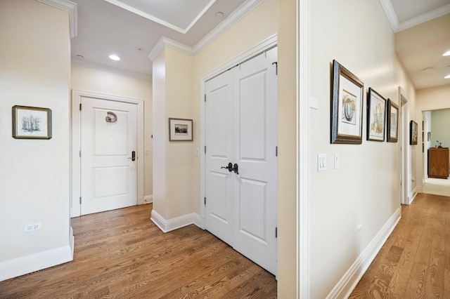 hallway featuring light wood-style floors, recessed lighting, baseboards, and crown molding