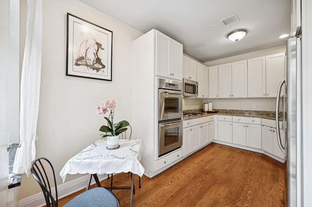 kitchen featuring white cabinets, appliances with stainless steel finishes, visible vents, and light wood-type flooring