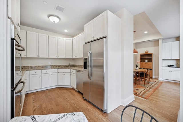 kitchen with white cabinets, stainless steel appliances, light wood finished floors, and visible vents