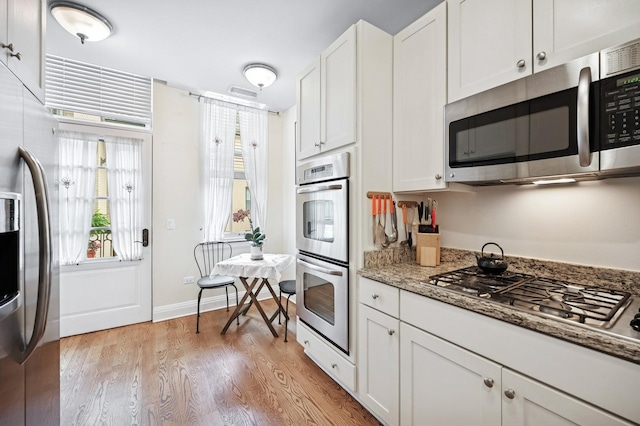kitchen featuring white cabinetry, appliances with stainless steel finishes, light stone counters, and light wood-style floors