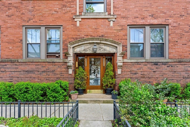 property entrance with fence and brick siding