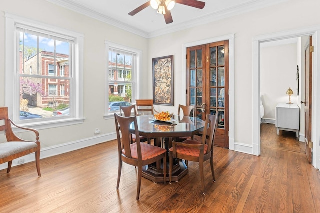 dining area featuring baseboards, ornamental molding, a ceiling fan, and wood finished floors