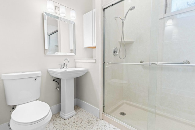 bathroom featuring baseboards, a stall shower, and toilet