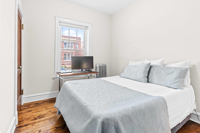 bedroom with baseboards, radiator heating unit, and wood finished floors