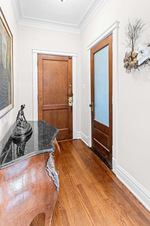 foyer with baseboards, ornamental molding, and wood finished floors