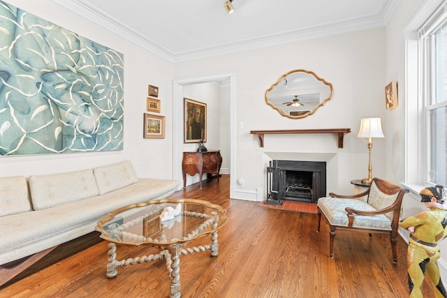 living area featuring crown molding, a fireplace with flush hearth, baseboards, and wood finished floors
