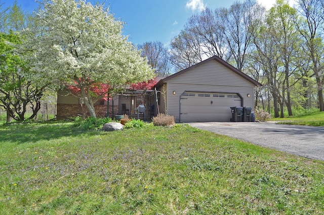 view of side of home featuring driveway, a yard, and an attached garage