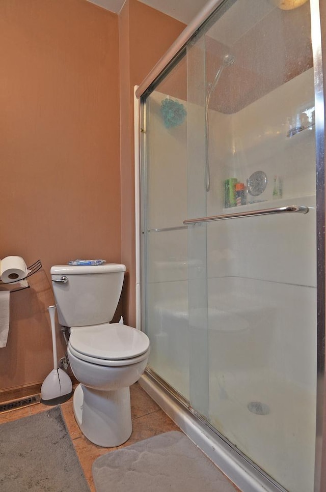 full bathroom with toilet, tile patterned flooring, and a stall shower