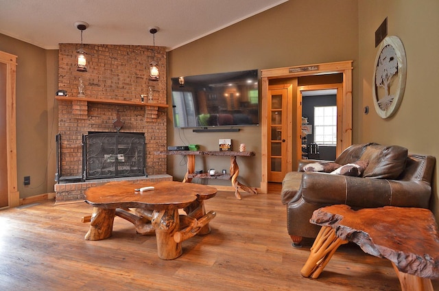 living room with a fireplace, wood finished floors, ornamental molding, and baseboards