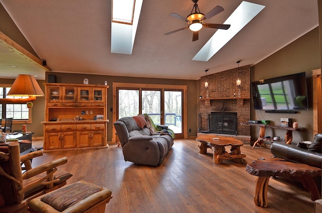 living room with a skylight, a ceiling fan, wood finished floors, and a healthy amount of sunlight