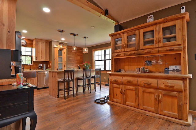 kitchen with a breakfast bar, dishwasher, light wood-style flooring, and plenty of natural light