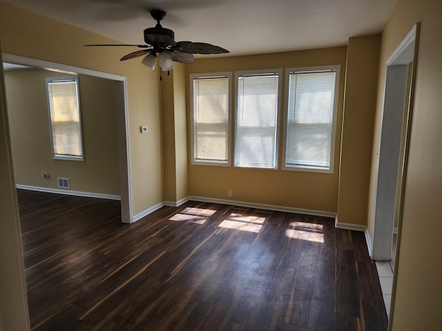 unfurnished room featuring baseboards, visible vents, a ceiling fan, and dark wood-type flooring