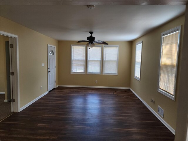 interior space with visible vents, ceiling fan, baseboards, and dark wood-type flooring