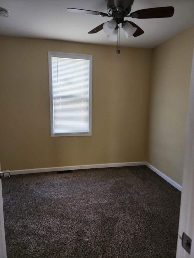 carpeted spare room featuring a ceiling fan and baseboards