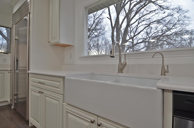 kitchen with dark wood-type flooring, cream cabinets, a sink, and light countertops