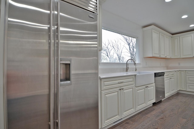 kitchen with a sink, appliances with stainless steel finishes, light countertops, recessed lighting, and dark wood-type flooring