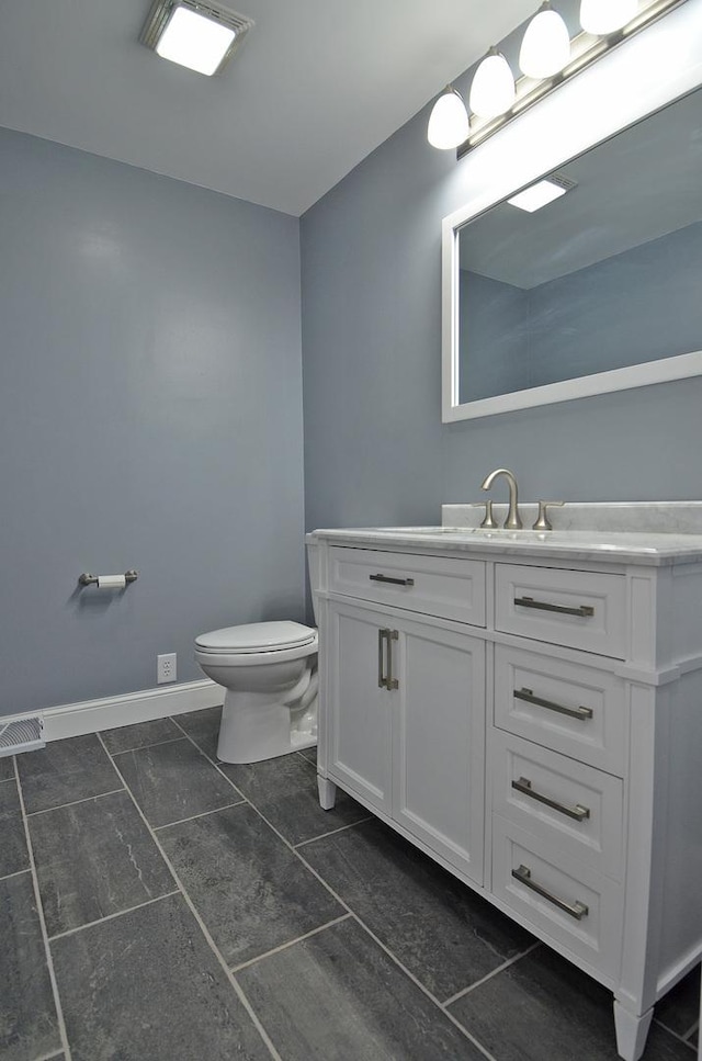 bathroom with tile patterned floors, toilet, vanity, baseboards, and visible vents
