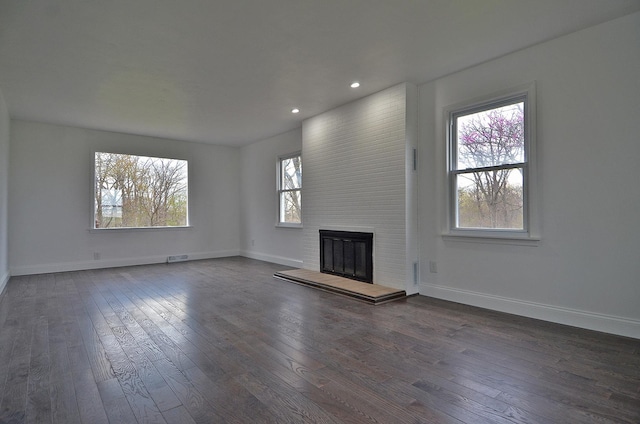 unfurnished living room with dark wood-style floors, recessed lighting, a large fireplace, and baseboards
