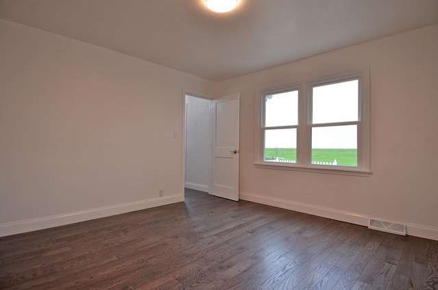 empty room with baseboards, visible vents, and dark wood-type flooring