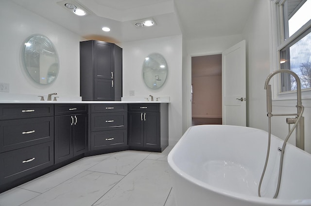 full bathroom with recessed lighting, a sink, marble finish floor, a freestanding bath, and double vanity