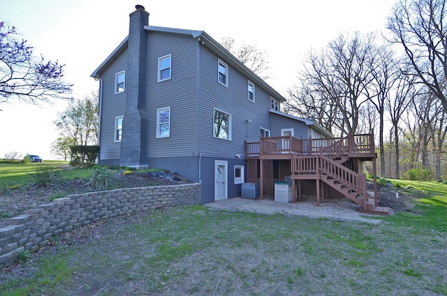 back of house with central air condition unit, a lawn, stairs, a chimney, and a deck