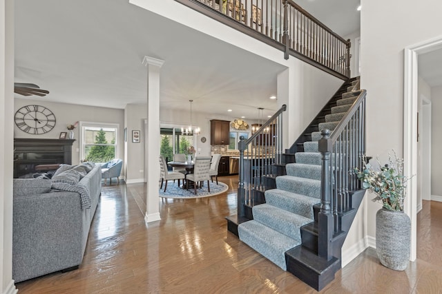 interior space featuring a glass covered fireplace, baseboards, ceiling fan with notable chandelier, and wood finished floors