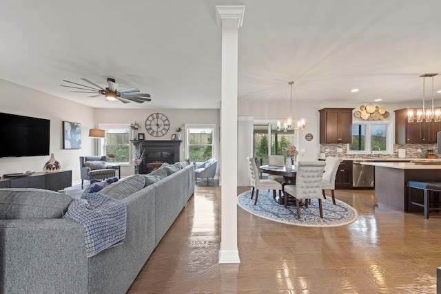 living area featuring a fireplace and ceiling fan with notable chandelier