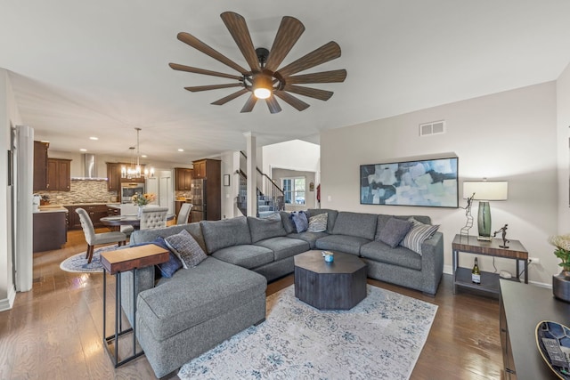 living area with visible vents, dark wood-type flooring, ceiling fan with notable chandelier, and recessed lighting