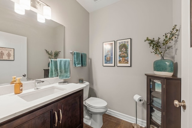 bathroom featuring baseboards, vanity, toilet, and wood finished floors