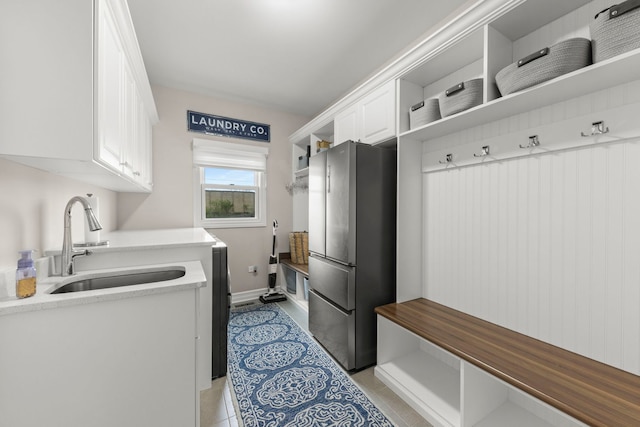 clothes washing area featuring baseboards, a sink, and light tile patterned floors