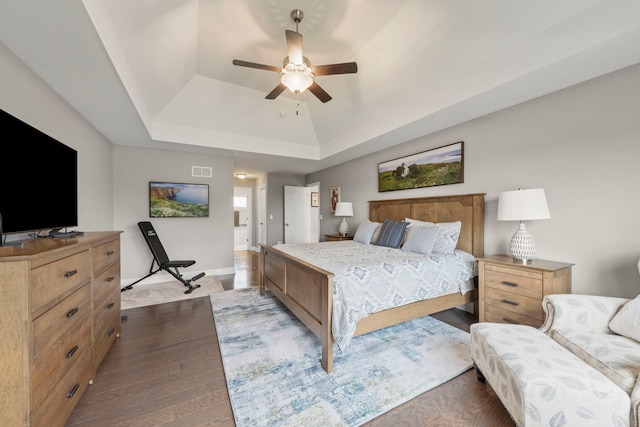 bedroom featuring visible vents, baseboards, ceiling fan, a raised ceiling, and dark wood finished floors