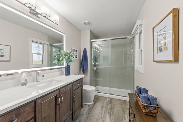 bathroom featuring visible vents, vanity, wood finished floors, toilet, and a shower stall